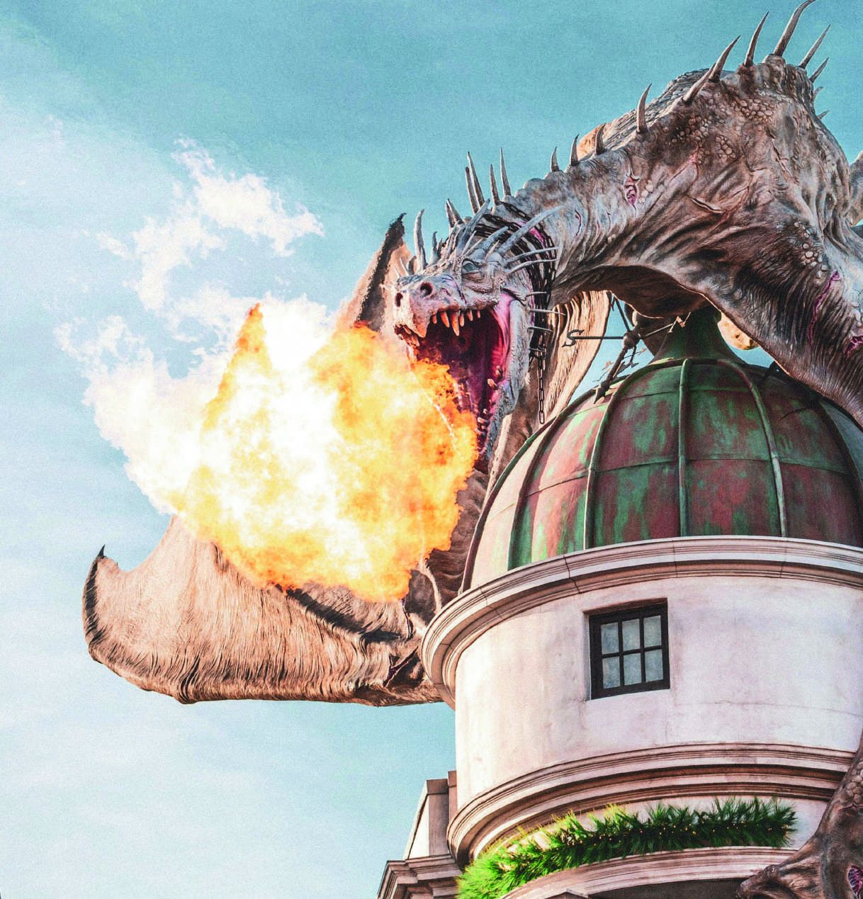 A fire-breathing dragon perched atop a domed wizarding bank against a pale sky